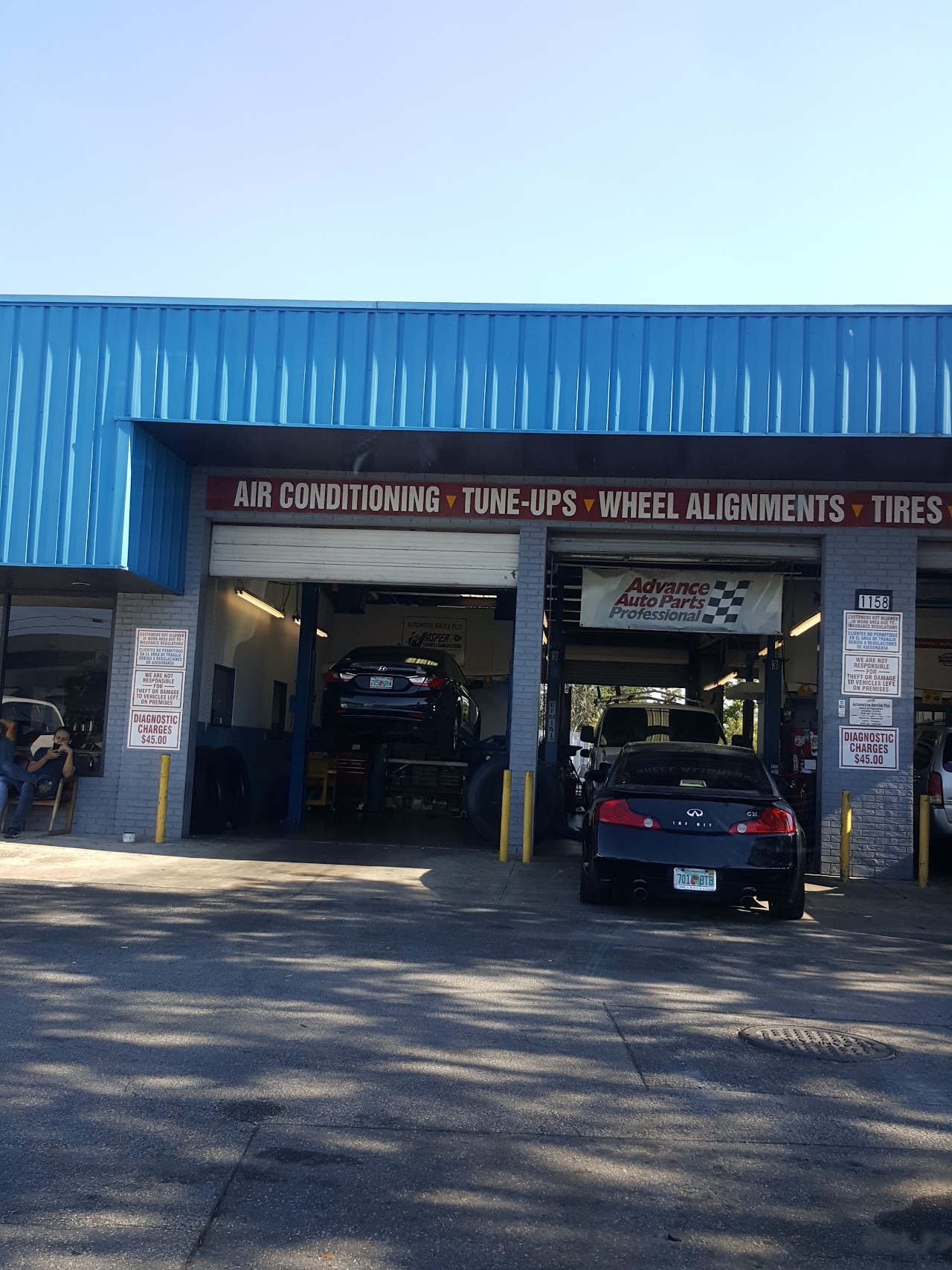 Exterior shot of a clean, modern brick auto repair facility with wide glass windows and multiple service bays, conveying a professional and welcoming atmosphere.